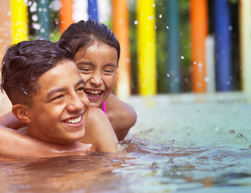brother and sister play in the pool with a colorful backdrop