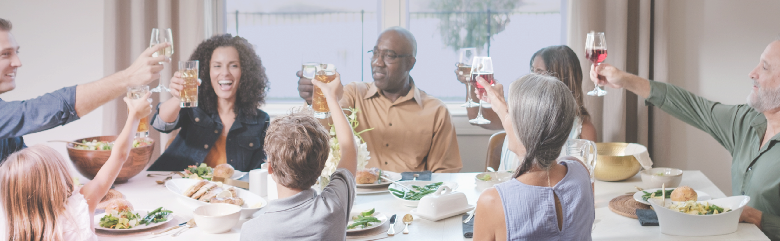 family and friends around a dining room table raising a glass in a toast