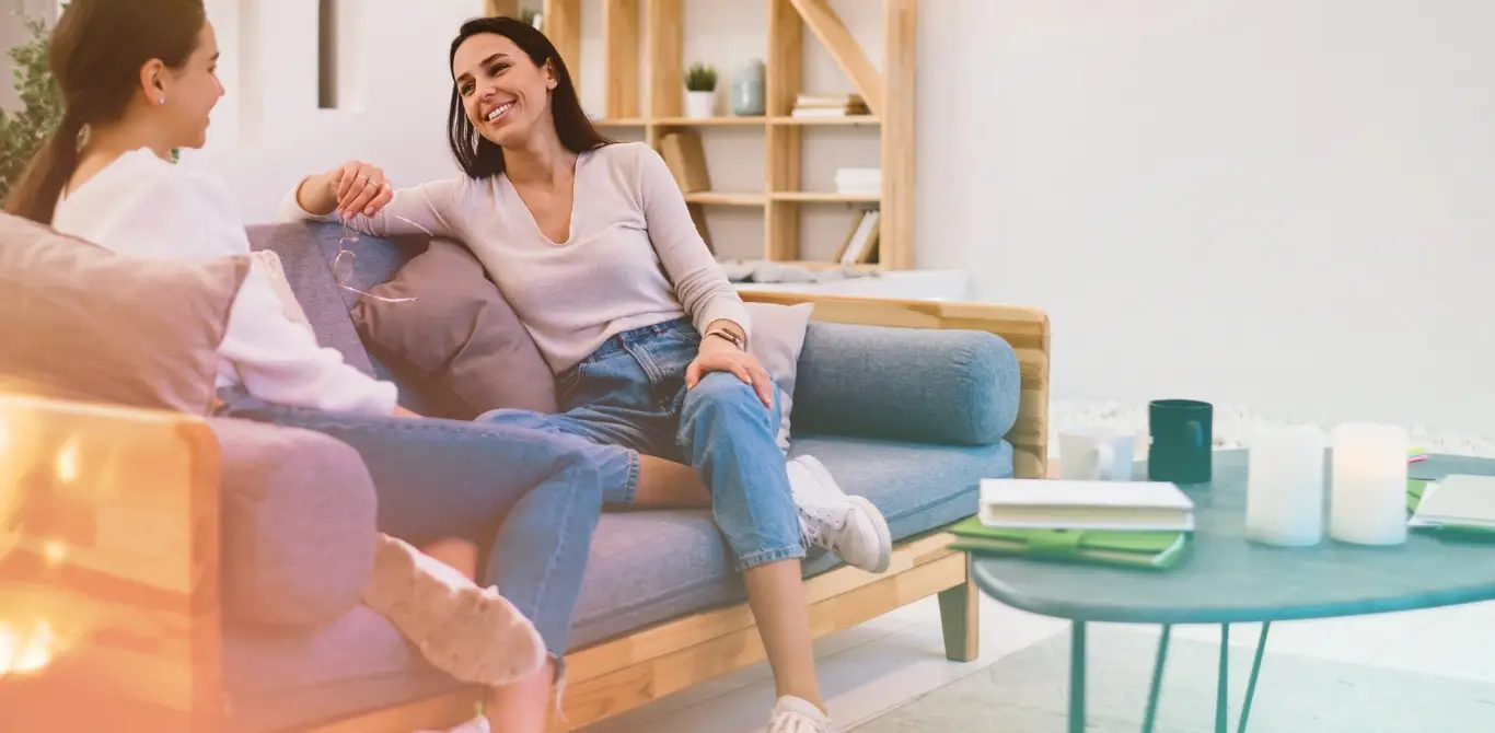 friends sit together in a lounge talking on a couch with notebooks and coffee - community is part of the vision for Hilliard Isle